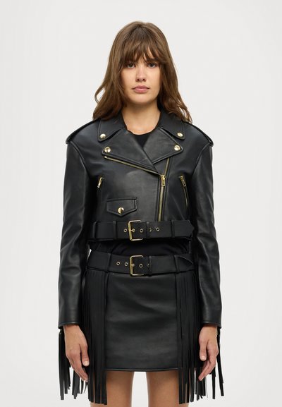 Giacca da moto in pelle nera con hardware dorato, zip asimmetrica, vita con cintura e dettagli in frangia lungo l'orlo e le maniche.