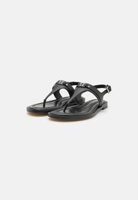 Zwarte lederen sandalen met een teenpostontwerp, met een open achterkant en zilveren accenthardware op de band. Platte zool, gladde textuur.