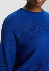 Blauer gestrickter Pullover mit strukturiertem Muster, offenen Maschen und einem gerippten Rundhalskragen. Glatte Oberfläche mit lockerer Passform.