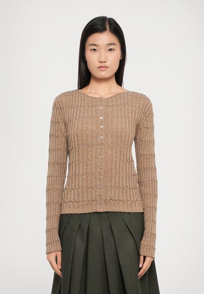 Lichtbruin gebreid cardigan met een ribbelstructuur, ronde halslijn en knoopsluiting, gecombineerd met een donkergroene geplooide rok.