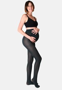 Collant maternità neri trasparenti, texture liscia, design a vita alta, aderenti fino a metà coscia, indossati con un reggiseno nero, modello che tiene la pancia.