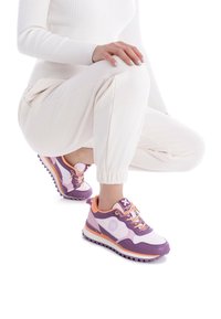 Zapatillas deportivas en tonos púrpura y rosa, con una combinación de materiales de cuero y malla. Presentan detalles en contraste, suelas gruesas y un sistema de cordones.