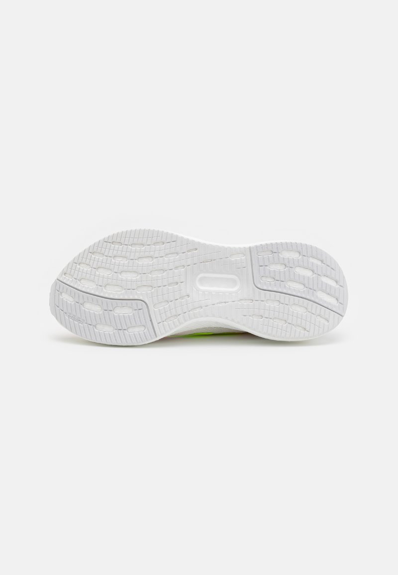 Suela de zapato con una superficie de goma blanca texturizada, que presenta surcos y patrones circulares para mayor tracción. Acentos verdes visibles cerca del talón.