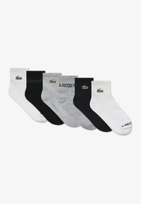 Set of six crew socks in white, gray, and black. Features Lacoste logo and branding. Made from cotton blend, ribbed texture.
