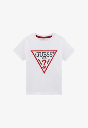 Bílý bavlněný tričko s krátkým rukávem, s červenou trojúhelníkovou grafikou a černým textem, který říká "GUESS U.S.A. WASCHED JEANS."