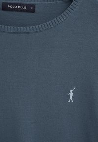 Blauer, gestrickter Pullover mit Rundhalsausschnitt und einem kleinen weißen Polospieler-Logo auf der Brust sowie einem Polo Club Markenetikett im Kragen.