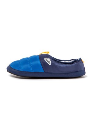 Navy and blue slipper with quilted front, yellow pull tabs, and white logo on the side, featuring a flat sole and soft interior lining.