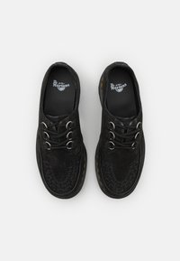 Fekete nubuk cipők texturált orr dizájnnal, kerek fűzőkkel, dupla lyukakkal és sárga varrású talppal. A belsejében Dr. Martens márkázás található.