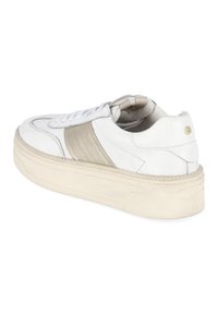Baskets basses blanches avec un détail de bande beige, lacets sur le devant et semelle épaisse blanc cassé, vues de côté arrière.
