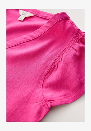 Różowy lniany top z dekoltem w serek, krótkimi rękawami i marszczeniami na ramionach. Gładka faktura, lekka tkanina.