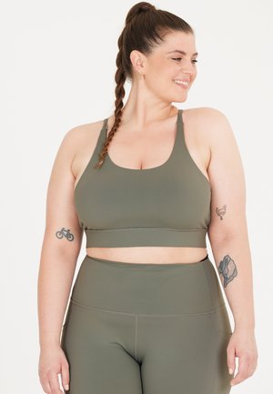 Olivgrön träningsset bestående av en åtsittande sport-bh med kraftiga remmar och högmidjade leggings, tillverkade av ett mjukt, elastiskt tyg.