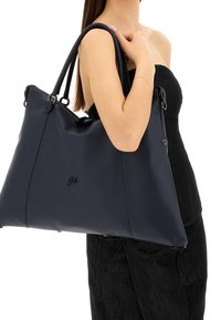 Borsa tote in pelle blu navy con finitura opaca, cuciture ben evidenti e dettagli in argento. Dotata di doppie spalline e chiusura con zip.