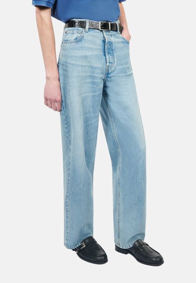 Lysblå wide-leg jeans lavet af denim med en falmet vask, der har et sort bælte med sølvhardware og en glat tekstur.