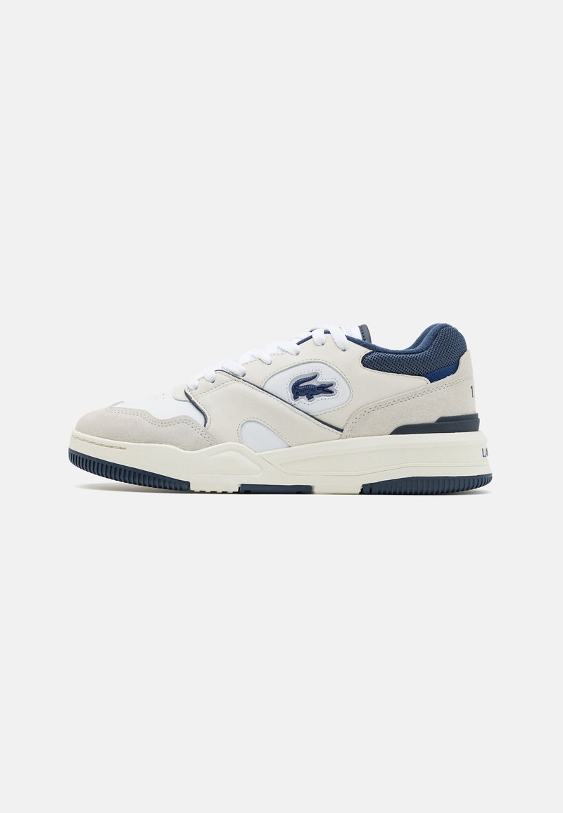Zapatillas de ante y malla en blanco y gris con acentos en azul marino, diseño con cordones, logotipo prominente en el lateral y suela de goma texturizada.