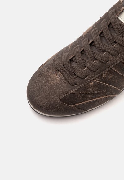 Gros plan d'une basket en cuir marron montrant des coutures détaillées et des lacets marron foncé bien serrés sur un fond blanc uni.