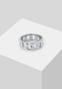 Anello in argento a catena con metallo lucido, caratterizzato da un design aperto e una texture liscia, che riflette la luce su uno sfondo neutro.