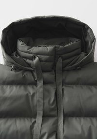 Dunkelgrüne Pufferjacke mit Kapuze. Verfügt über gesteppte Bereiche, verstellbare Kordeln und eine weiche, glatte Textur.