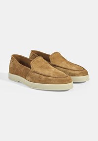 Wildleder Slipper in Hellbraun mit einer runden Zehenpartie, die eine gestickte Akzentuierung an der Vorderseite und eine kontrastierende Gummisohle aufweist.