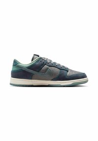 Low-top Nike-tennarit sinisenä ja harmaana mokka- ja verkkopaneeleilla, teal-ompeleilla ja läpikuultavalla pohjalla, esitetty sivuprofiilista.