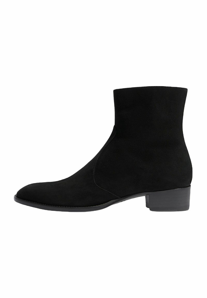 Botas de tobillo de ante negro con puntera afilada y un tacón bajo tipo bloque. El diseño presenta costados verticales sin costuras y una textura suave.