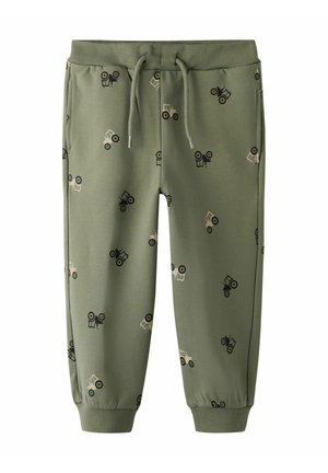 Grüne Sweatpants mit einem elastischen Bund und Kordelzug. Mit kleinen Traktoren in Schwarz und Beige gemustert. An den Knöcheln umgeschlagen.