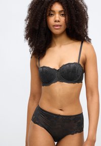 Črni čipkasti modrček in hlačke z visokim pasom, s cvetličnimi vzorci, nastavljivimi naramnicami in nazobčanimi robovi za dodatne podrobnosti in teksturo.