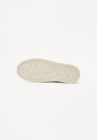 Semelle en caoutchouc crème avec le texte « KENNEL SCHMENGER » en relief et des étoiles. Surface texturée avec des rainures pour l'adhérence. Design plat.