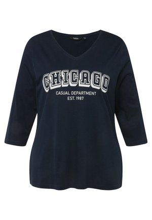 Granatowa koszulka T-shirt z dekoltem w serek i rękawami trzy czwarte, z białym nadrukiem graficznym, na którym napisano "CHICAGO CASUAL DEPARTMENT EST. 1987."