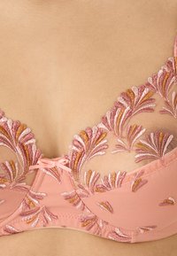 Brasiletta rosa tenue con ricami floreali in tonalità di rosa e arancione, caratterizzata da un morbido materiale in rete, dettagli in pizzo e un accento centrale a fiocco.