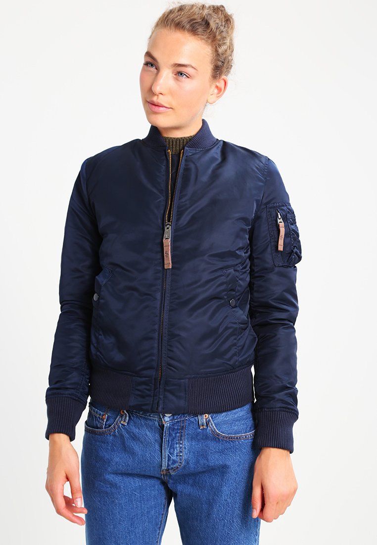 Chaqueta bomber de la Marina de color azul con cierre de cremallera en el frontal, puños y dobladillo acanalados. Presenta un bolsillo tipo parche en la manga izquierda y está confeccionada con una tela suave y brillante.