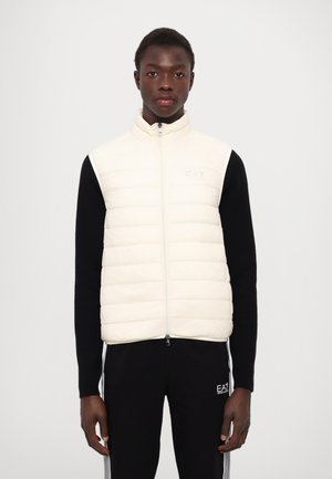 Gilet imbottito senza maniche color crema con design trapuntato e colletto alto. Presenta una zip frontale e un logo sottile sul petto.