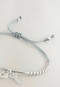 Verstellbares hellgraues Kordelarmband mit Silberperlen und kleinen silbernen Schlüsselanhängern auf hellem Hintergrund.