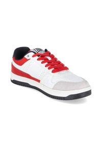 Basket blanche basse avec lacets rouges, accents en daim rouge, doublure intérieure noire et semelle en caoutchouc noir, inclinée pour montrer le côté extérieur et l'avant.