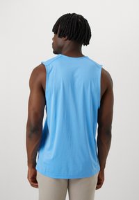 Helles blaues Trägershirt mit einem runden Ausschnitt und ärmellosem Design. Weiche Textur, leichter Glanz und lockere Passform.