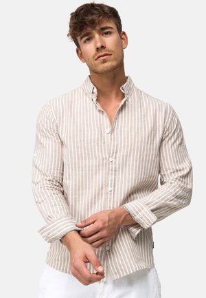 Camicia con bottoni, a strisce verticali beige e bianche, realizzata in un tessuto testurizzato, con colletto ripiegato e dettagli sui polsini.