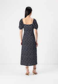 Vestido floral azul-marinho com mangas bufantes, costas quadradas e design até ao tornozelo; apresenta pequenos padrões de flores brancas e uma textura fluida.