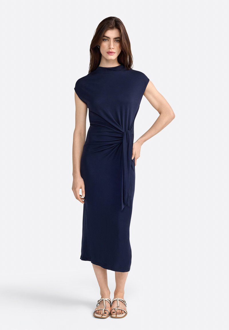 Vestido azul marino, hasta la rodilla, con silueta ajustada, mangas cortas y detalle de nudo en la cintura. Tejido suave y elástico, textura lisa.