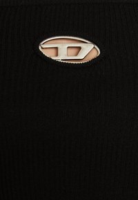Černá ribbovaná tkanina s výřezem, který zdobí stříbrný oválný akcent. Textura je hladká a design je přiléhavý.