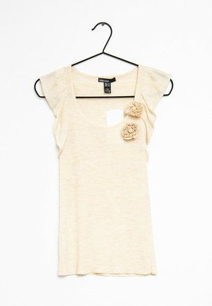 Krémový top s krátkým rukávem a kulatým výstřihem, na levé straně zdobený dvěma textilními květinovými aplikacemi. Měkký, lehký materiál.