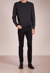 Ciemnoszary sweter z dzianiny z prążkowanym dekoltem, zestawiony z czarnymi dżinsami slim fit i czarnymi botkami za kostkę. Gładka textura, dopasowany krój.