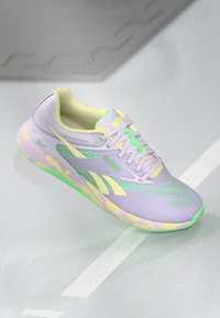 Helllila Laufsschuh mit grünen Akzenten. Verfügt über ein Obermaterial aus Mesh, eine gemusterte Sohle und kontrastierende gelbe Details. Schnürdesign.