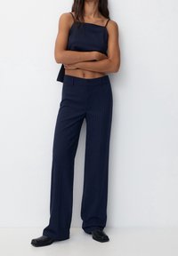 Marineblauwe gestreepte crop top en wijde broek van een soepele stof. Eenvoudig ontwerp met dunne bandjes en een aansluitende tailleband.