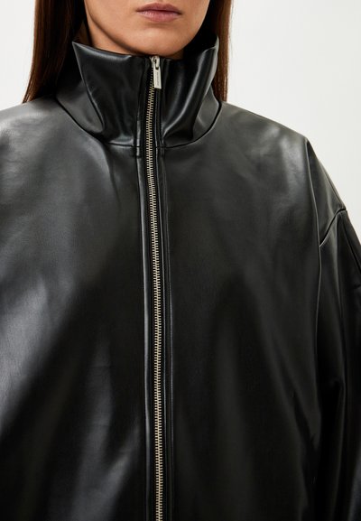 Black leather jacket with a high collar, featuring a full-length silver zipper and smooth texture, designed with dropped shoulders.
