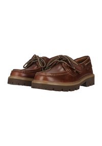 Chaussures bateau en cuir marron avec semelles épaisses à crampons et lacets rayés noués en nœuds, présentées côte à côte sur fond blanc.