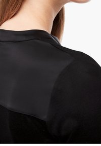 Zwart top met een gladde satijnen schouderpartij en een gestructureerde jersey stof op het lichaam, met een eenvoudige, moderne snit.