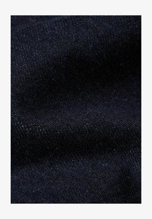 Primer plano de tela texturizada azul oscuro con patrón de tejido visible y suaves pliegues.