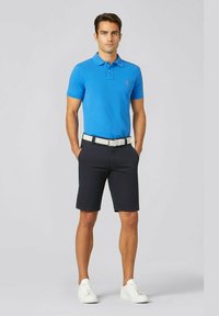 Polo shirt bleu, shorts bleu marine, ceinture blanche et baskets blanches. Manches courtes, col classique, coupe droite. Pas de motifs ni d'accents.