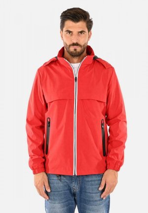 Giacca impermeabile rossa con chiusura a zip, cerniere nere a contrasto, due tasche laterali e polsini elasticizzati; progettata in un materiale leggero.