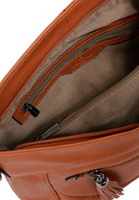 Interno di una borsa in pelle marrone chiaro con fodera in nylon, dotato di una tasca con zip e un'ulteriore tasca a slip, accentuato da hardware in argento.