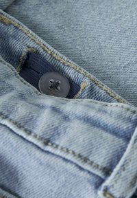 Hele sinine teksariidest kangas, millel on nööpkinnitus ja kontrastne beež õmblus, mis näitab tekstuuriga pinda ja voltitud kangast detaili.